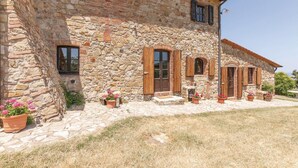 A stone building with a rustic appearance, featuring multiple windows with shutters, a central door, and potted plants. - Cozy apartment in Montecatini V.C. (FI) (Montecatini V.C. (FI))