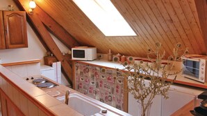 Une cuisine de taille réduite, avec des poutres en bois, un puits de lumière et des appareils électroménagers de base.