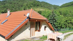 Une maison avec un toit en pente, une antenne parabolique et une petite terrasse avec une table et des chaises.