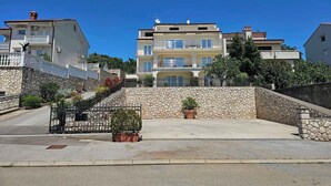 Un edificio a più piani con balconi, un muro in pietra e piante in vaso.