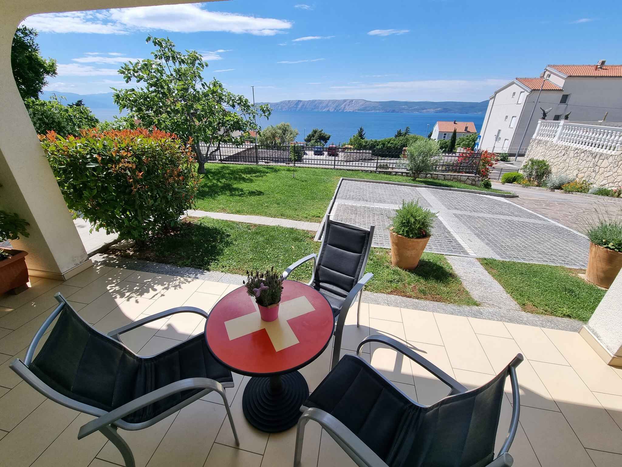 A patio with a table and chairs, a view of the sea, and a stone wall.