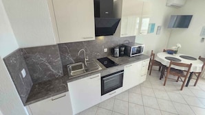 Una cucina moderna con lavello, piano cottura, forno a microonde e un'area pranzo con sedie e tavolo.