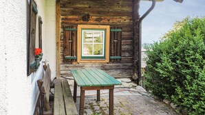 Eine rustikale Holzhütte mit einer hölzernen Bank und einem Tisch davor, einem Fenster mit Fensterläden und einer grünen Tür.