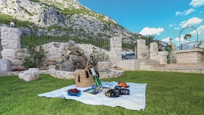 Een picknickopstelling op een gazon met een stenen muur en een berg op de achtergrond.
