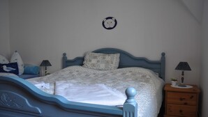 A bedroom with a bed, a nightstand, a wall clock, and a small plant. - FeWo Möwennest / Felstehausen GM 69252 - FeWo Möwennest (Graal-Müritz)