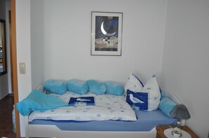 A bedroom with a bed, pillows, a nightstand, a lamp, and a framed picture on the wall.
