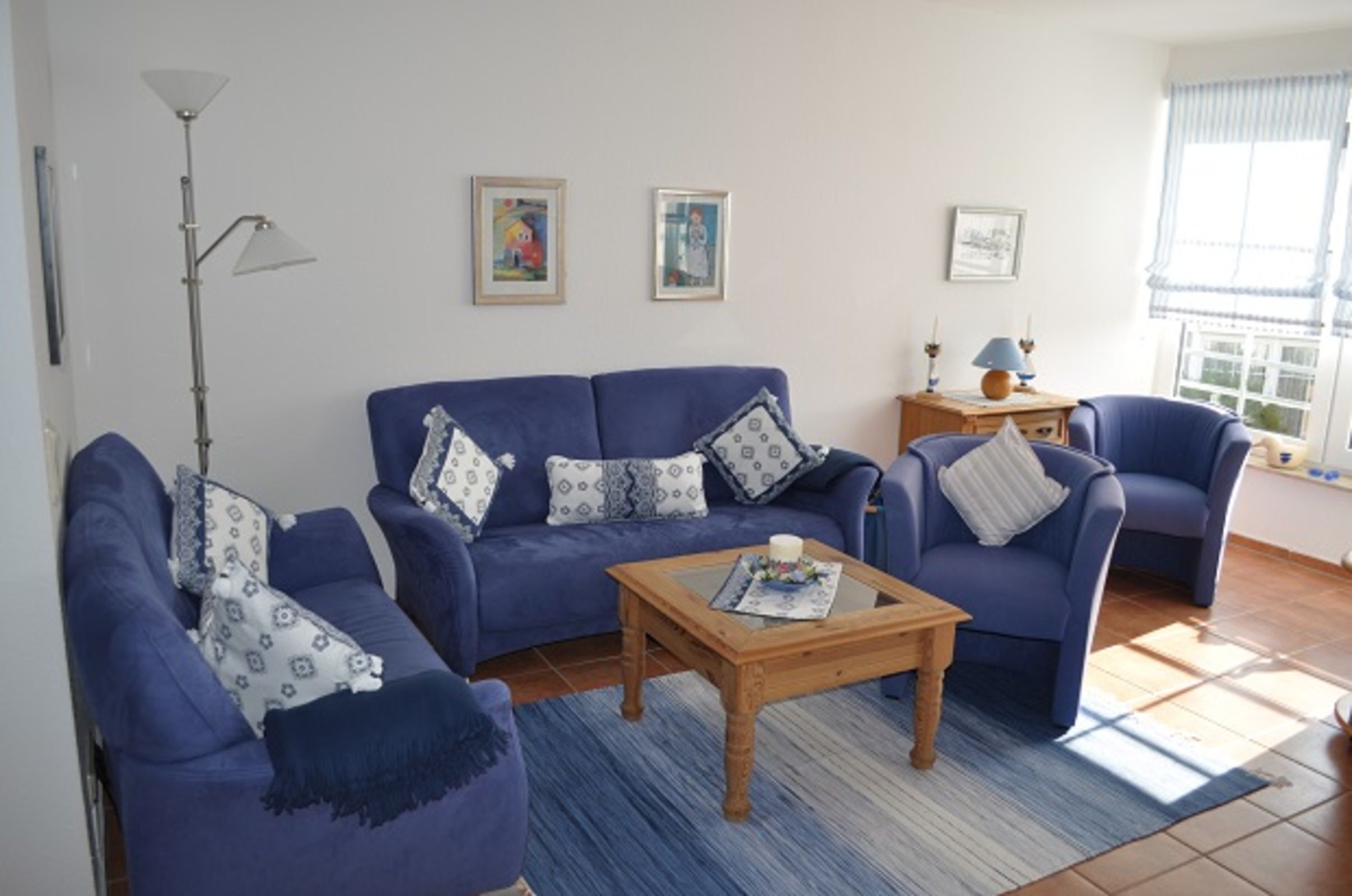 Ein Wohnzimmer mit einem blauen Sofagarnitur, einem Holztisch und einer Stehlampe.