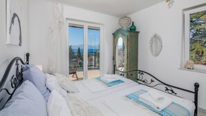 Une chambre avec un lit, une vue sur la mer, un balcon et un miroir décoratif.