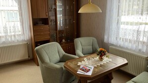 Una stanza con due poltrone, un tavolo in legno con un vaso e una vetrina contenente diversi oggetti.