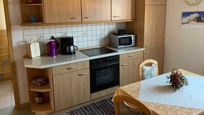 Una cucina con mobili in legno, un forno a microonde, una macchina da caffè e un tavolo con tovaglia in pizzo.