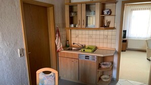 Una cucina compatta con mobili in legno, un lavello e un piccolo angolo ristoro.