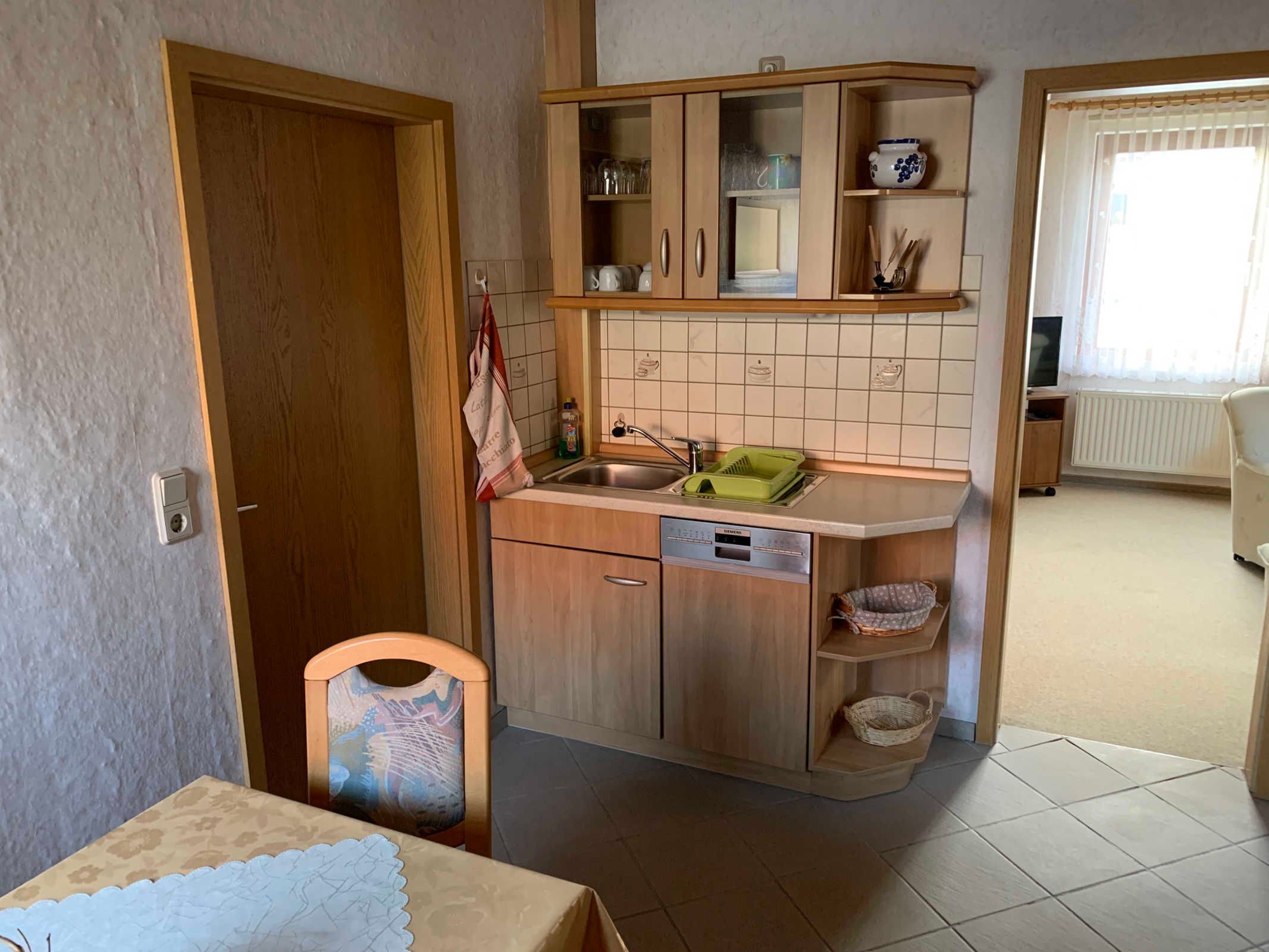 Une cuisine compacte avec des meubles de rangement en bois, un évier et un petit coin repas.