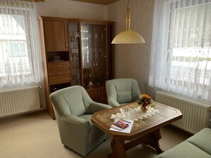 A room with two armchairs, a wooden table with a vase, and a glass cabinet with various items. - FW 2 (in the house) - Apartments Rießling (Elend)