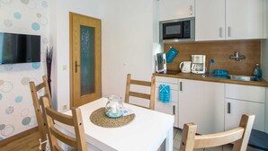Une cuisine compacte avec des meubles blancs, un four à micro-ondes, une machine à café et un évier.