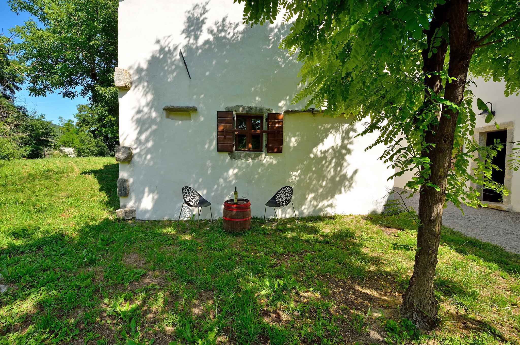 Un edificio bianco con una piccola finestra e una botte rossa davanti.