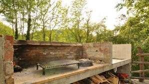 An outdoor brick oven with a metal grill and a sink, surrounded by stacked firewood. - Holiday home in a quiet location for nature lovers (Buzet)