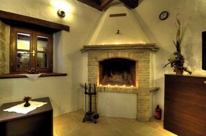 Cozy room with a fireplace, wooden mantel, and window, featuring a small table, candelabra, and clock.