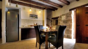 A kitchen with a wooden table and chairs, a refrigerator, and a stone wall. - Holiday home in a quiet location for nature lovers (Buzet)