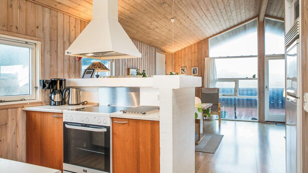 Una cocina moderna con paredes de madera, horno empotrado y un ventanal grande.