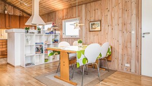 Una habitación acogedora con paneles de madera, una mesa de comedor, sillas y una estantería.
