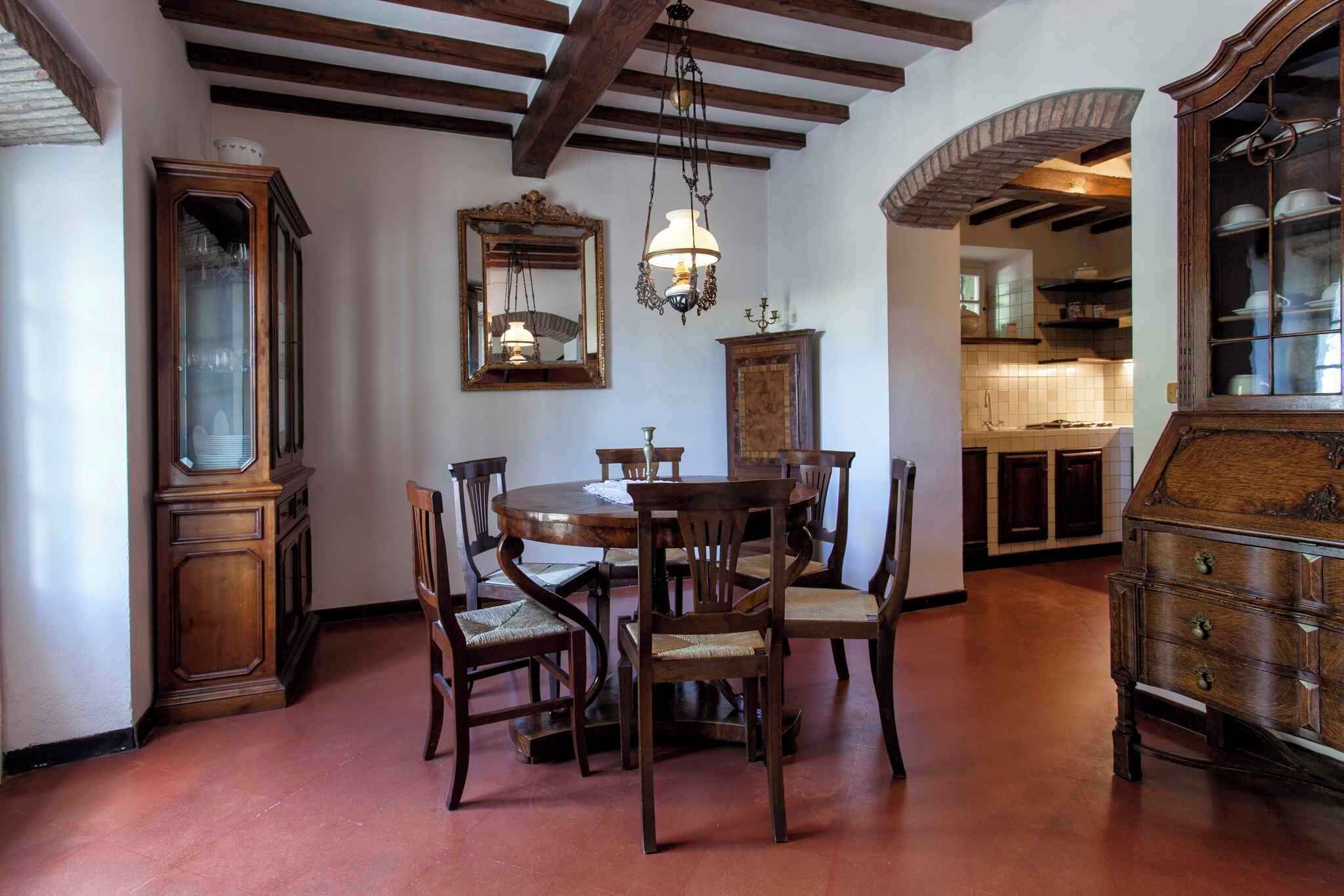 A dining area with a wooden table and chairs, a chandelier, and a mirror on the wall.