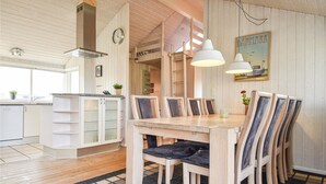 Un intérieur en bois comprenant une table à manger, des chaises, un coin cuisine et un tableau représentant le Danemark.
