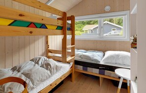 A bunk bed room with a window view of houses and greenery.