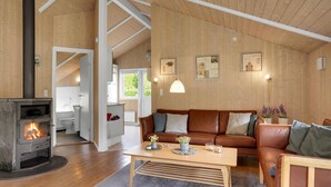 A cozy living room with a fireplace, wooden walls, a sofa, and a coffee table. - Awesome home in Juelsminde with sauna (Juelsminde)