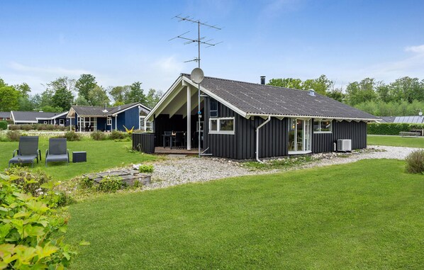 A modern house with a large deck, a satellite dish, and a chimney.