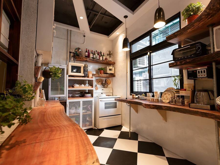 A compact kitchen with a checkered floor, wooden counter, and various kitchen appliances.