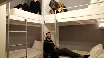 A bunk bed room with metal railings, a hanging light fixture, and a wall clock.