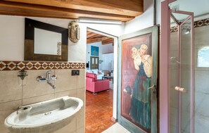 Ein Badezimmer mit Waschbecken, Spiegel und einer Tür mit einem Gemälde.