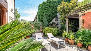Une cour avec deux fauteuils, une table et des plantes en pot.