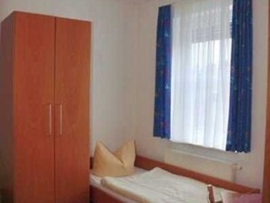 A room with a bed, a wardrobe, and a window with curtains.