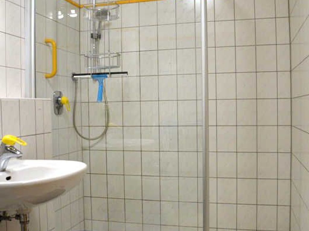 A bathroom with a sink, shower, and tiled walls.