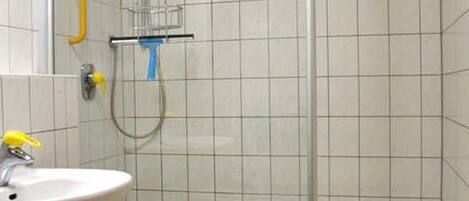A bathroom with a sink, shower, and tiled walls.
