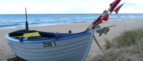 Una pequeña embarcación con el número 'ZIW 1' sobre una playa arenosa.
