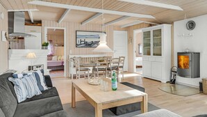 A modern living room with a wooden dining table, a sofa, and a fireplace. - 3 bedroom lovely home in Melby (Melby)