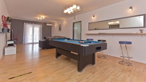 A spacious living area with a pool table, a sofa, and a bar area with stools. - Awesome home in Frkeci (Frkeci)
