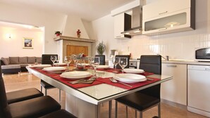 A dining area with a rectangular table set for four, surrounded by black chairs. There is a kitchen area with a microwave and a coffee maker visible. - Awesome home in Frkeci (Frkeci)