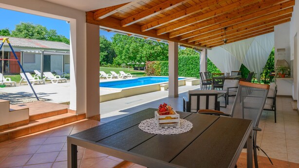 A covered outdoor area with a pool, lounge chairs, and a table with a cake. - Awesome home in Frkeci (Frkeci)