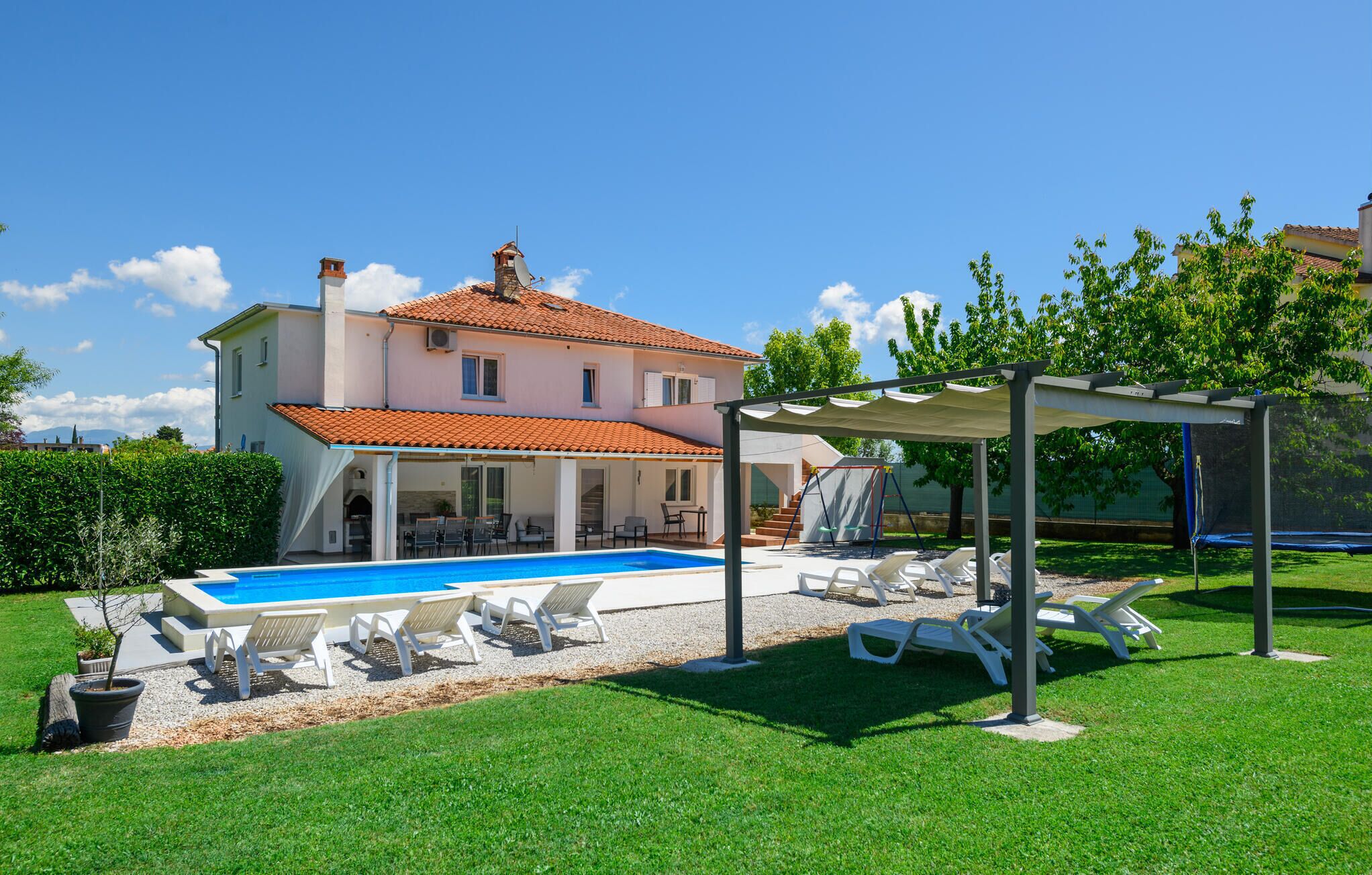 A two-story house with a swimming pool, outdoor seating, and a covered patio area.