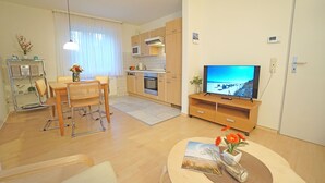 Ein modernes Wohnzimmer mit Essbereich, Küche und Fernseher auf einem Holzboden.