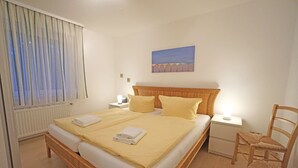 Ein Schlafzimmer mit einem Bett, einem Nachttisch, einem Sessel und einem Bild an der Wand.