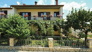 Ein zweistöckiges Gebäude mit Balkon, Steinmauern und einem Schotterweg.