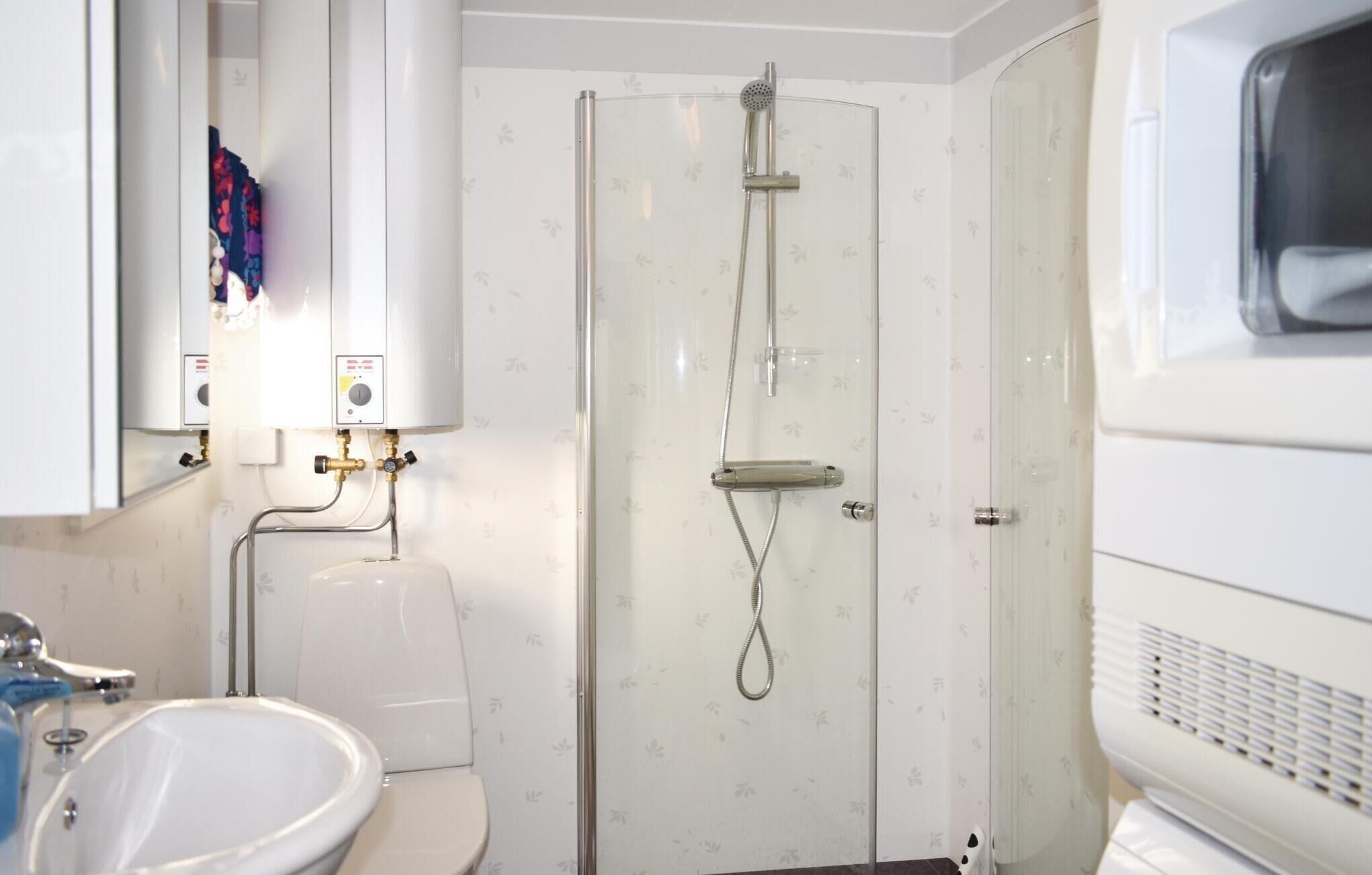 Une petite salle de bain comprenant des toilettes, un lavabo, une douche et un radiateur blanc.