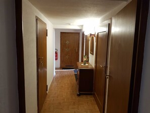 Ein Flur mit Holztüren, einem Feuerlöscher und einem kleinen Tisch mit einer Vase.