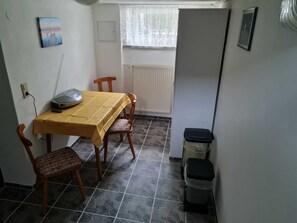 Ein kleiner Essbereich mit Tisch, Stühlen, einem Heizkörper und einem Mülleimer.