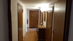 A hallway with wooden doors, a fire extinguisher, and a small table with a vase. - Apartment in Ahlbeck - Apartment (basement up to 3 pers.) (Heringsdorf)
