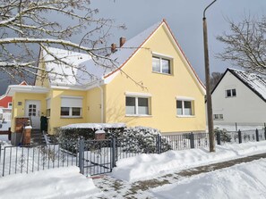 A yellow house with a red roof, a gated entrance, and a brick pathway leading to the door. - Apartment in Ahlbeck - Apartment (basement up to 3 pers.) (Heringsdorf)